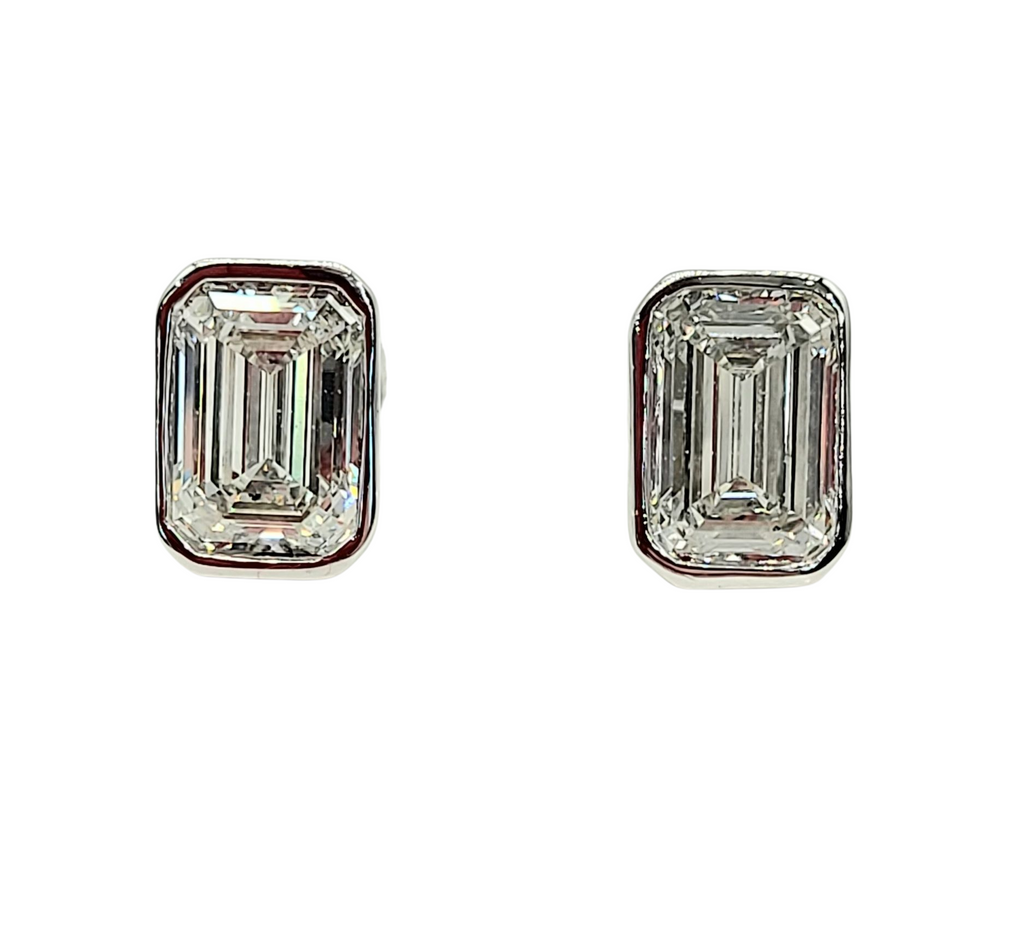 Pair of emerald-cut diamond earrings on a white background