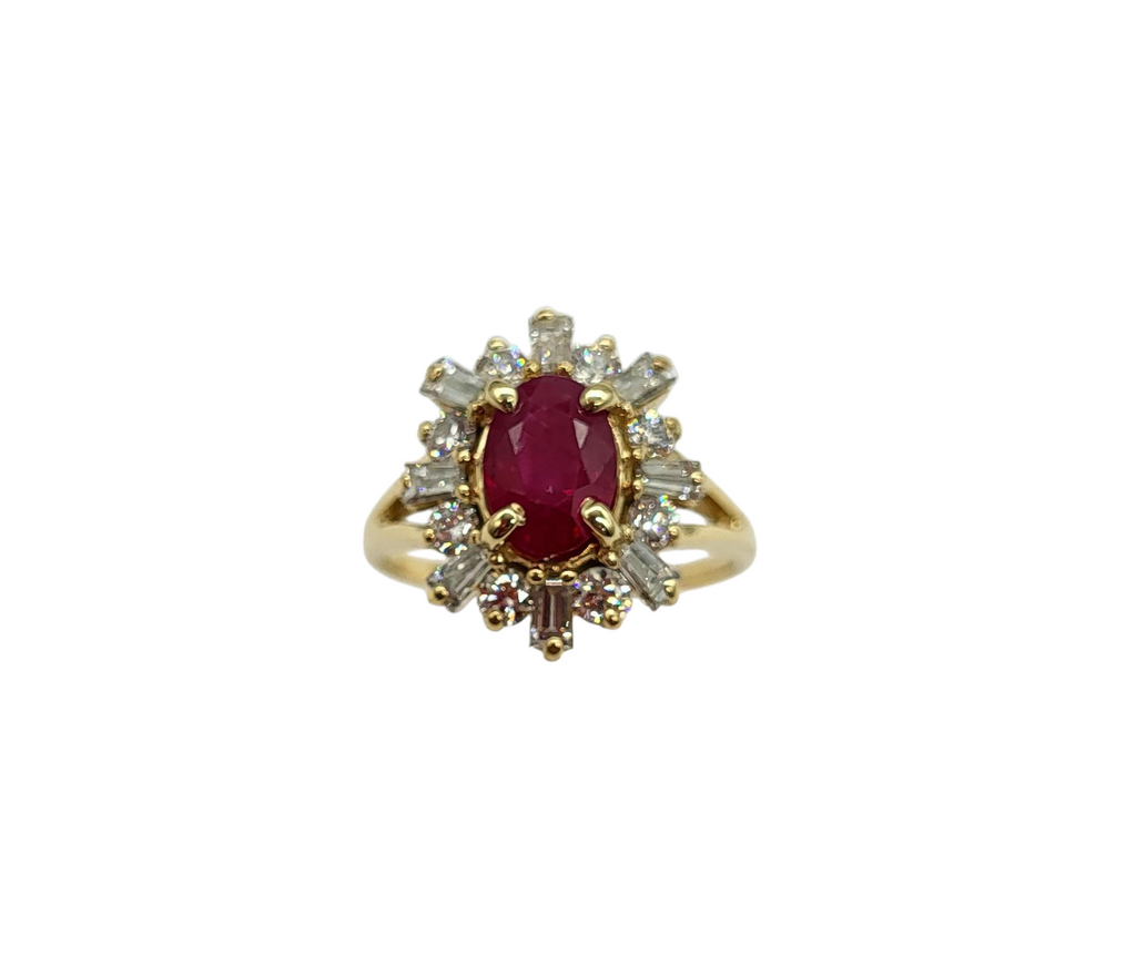 Gold ring with a red gemstone and diamond accents on a white background