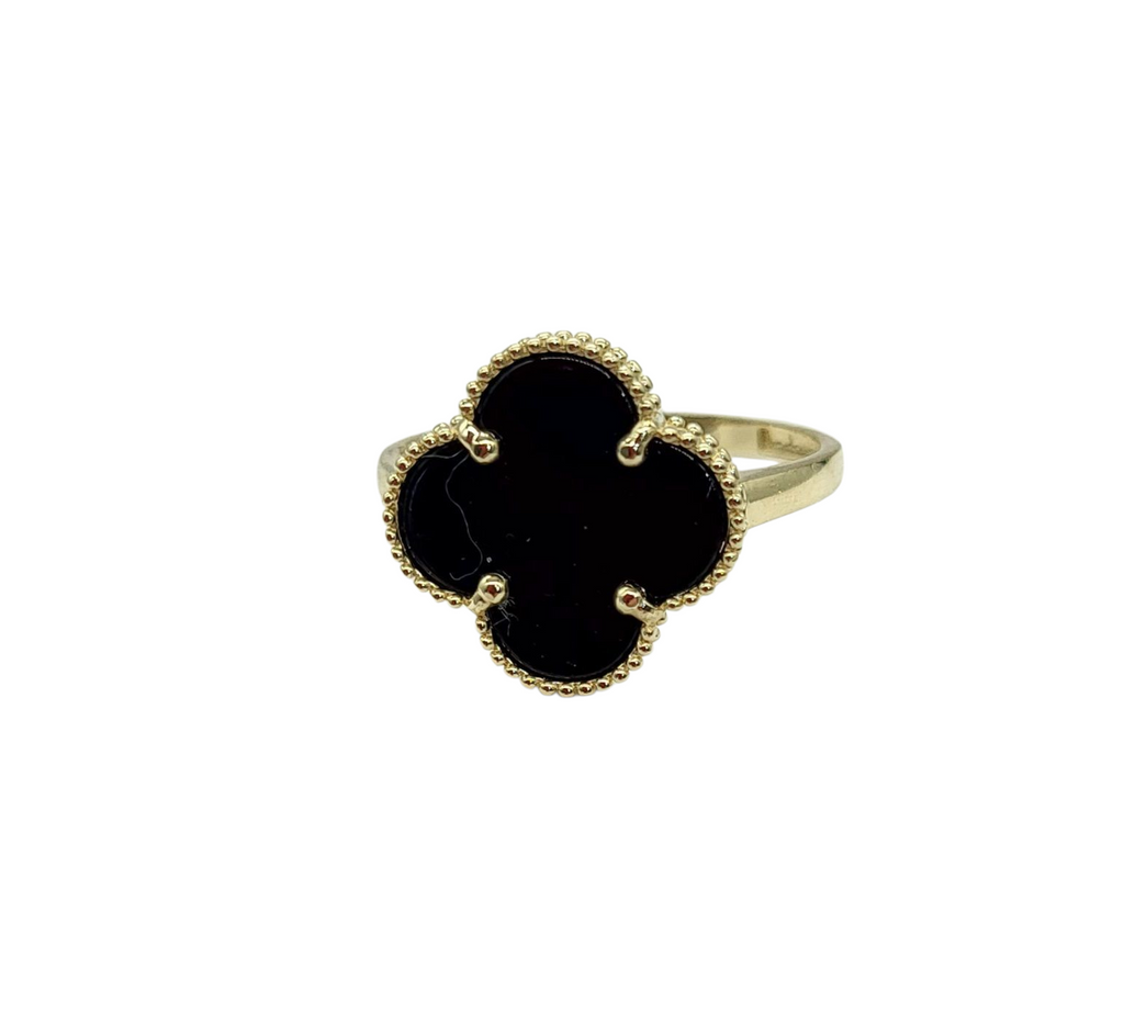 Gold ring with a black clover-shaped stone on a white background