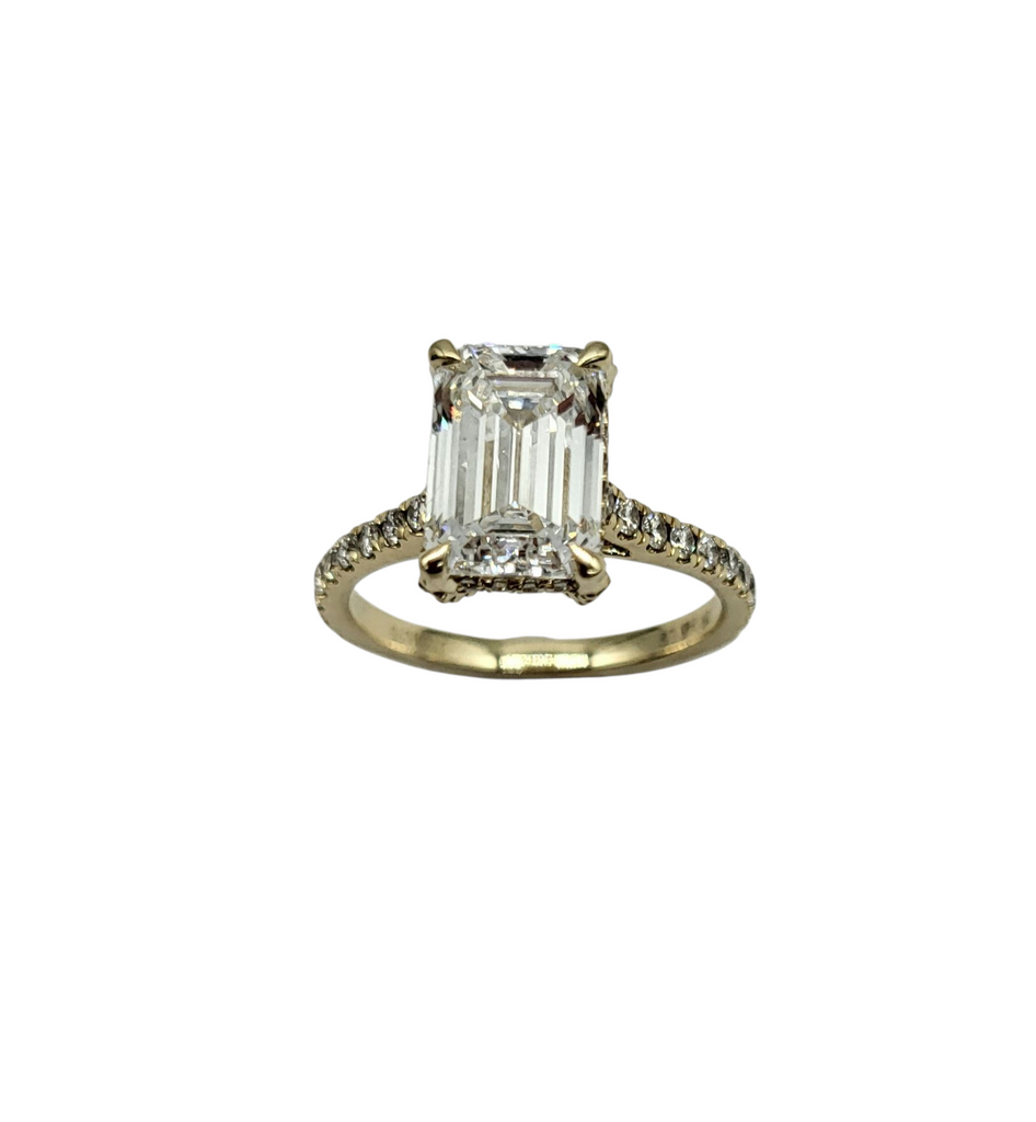 Diamond ring with emerald-cut center stone on a white background