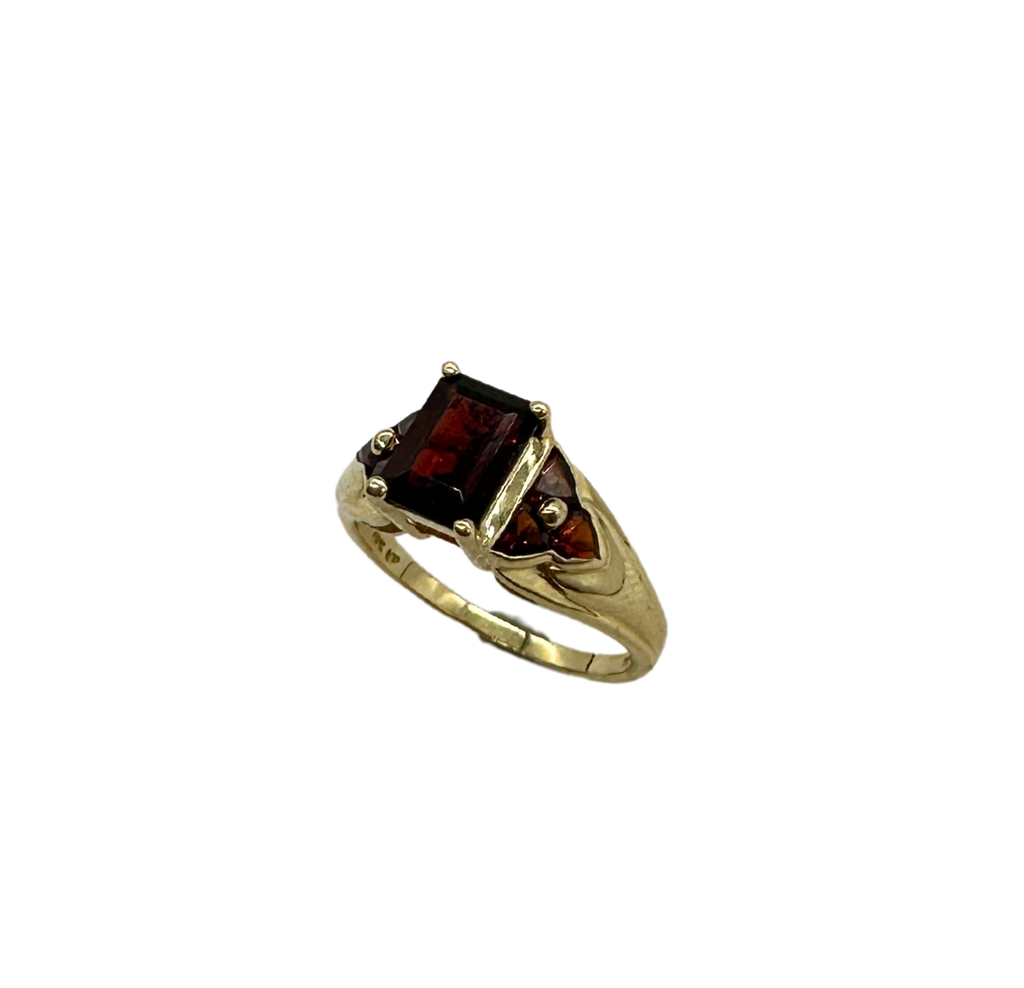 Gold ring with a garnet stone on a white background
