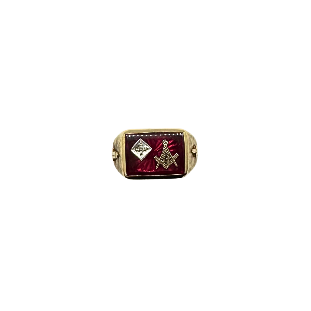 Gold ring with red stone and Masonic symbols on a white background