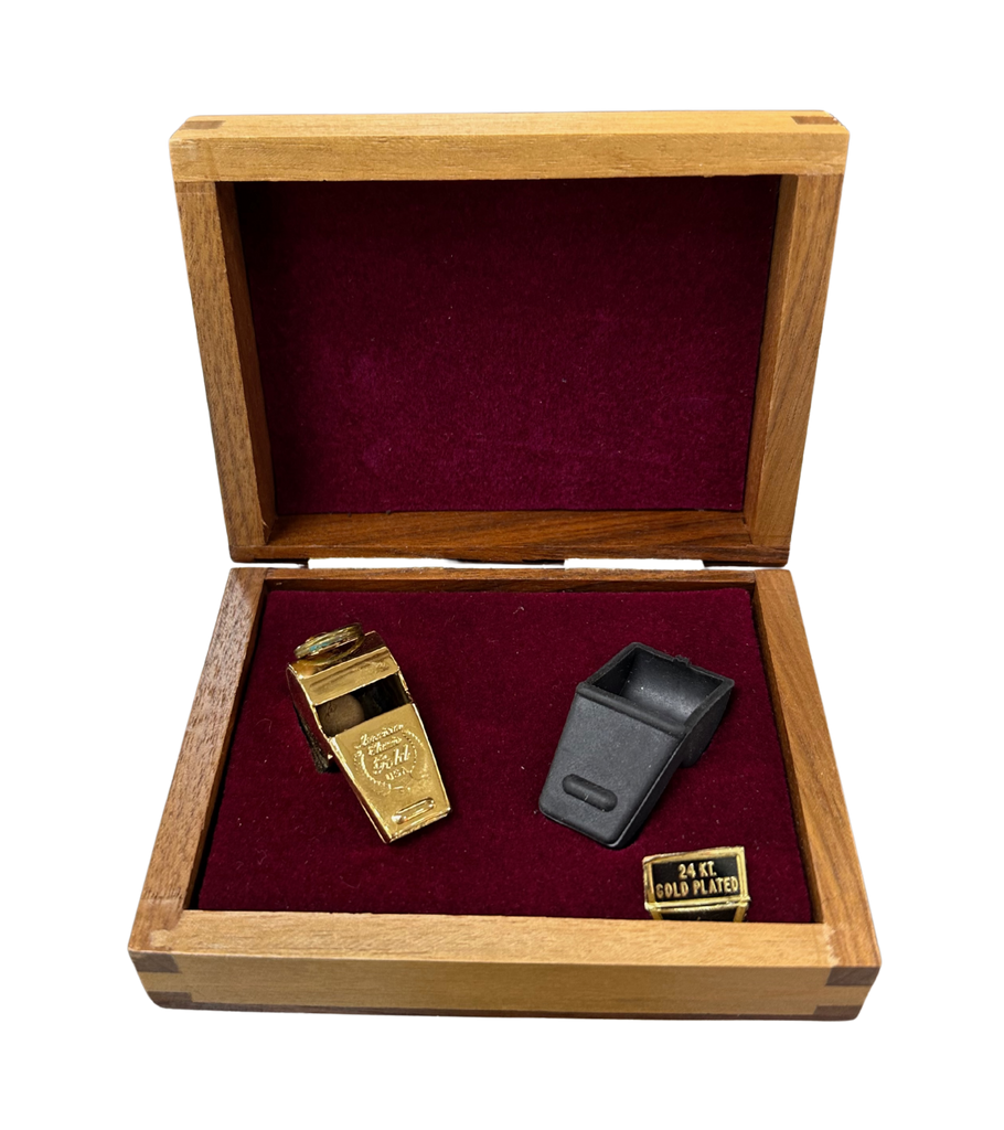 Gold and black whistles in a wooden box with red interior