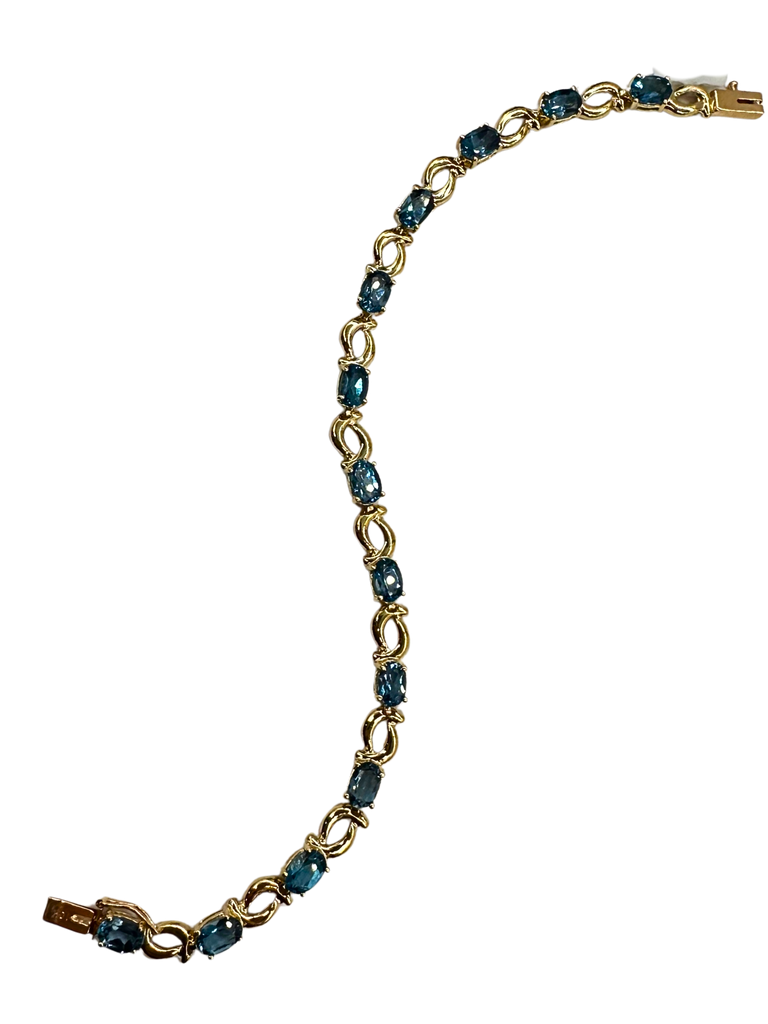 Gold bracelet with blue gemstones on a white background