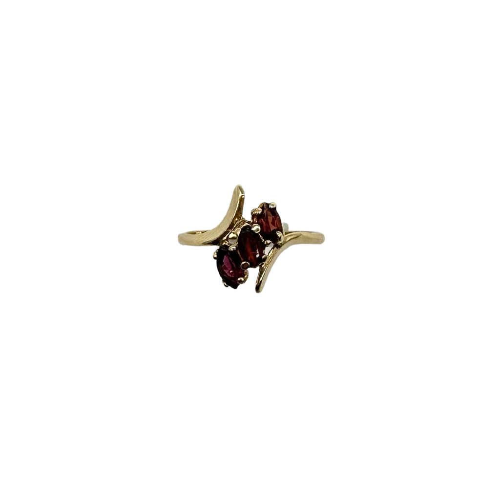 Gold ring with three red gemstones on a white background