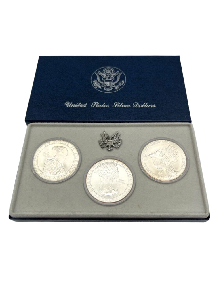 Set of three silver coins in a United States Silver Dollars display case on a white background