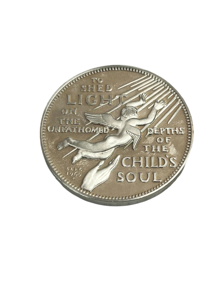 Silver coin with angelic design and text on a gray background